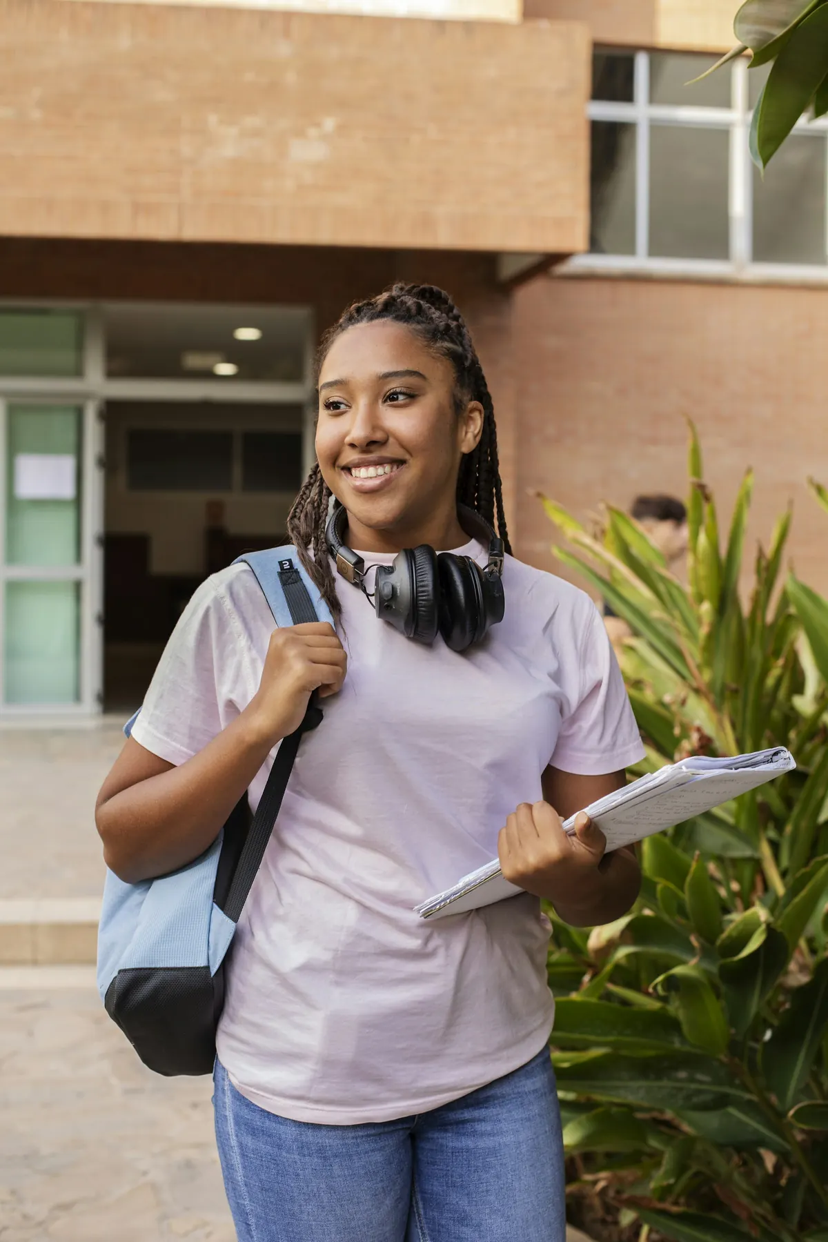 Student with backpack and notes on a university campus